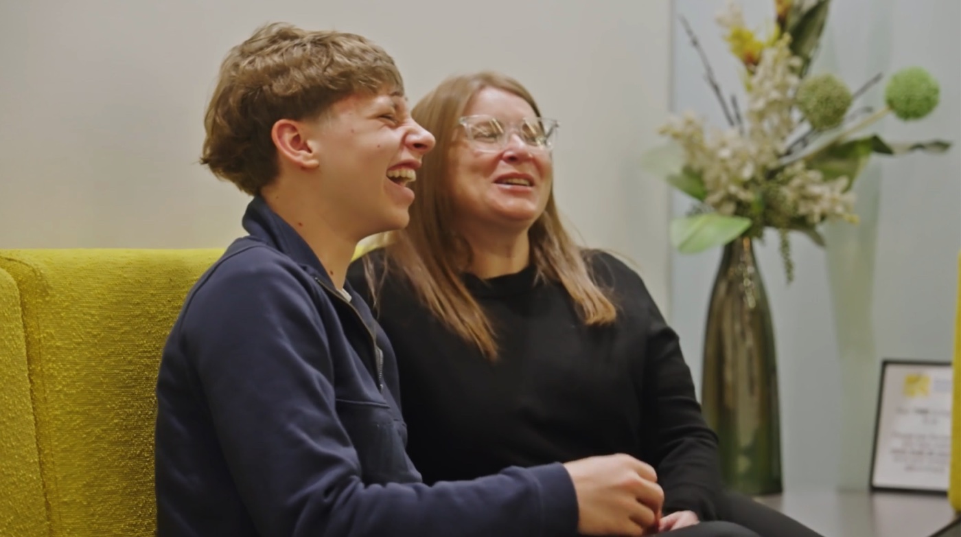 Teen patient laughing with his mother after finishing orthodontic treatment