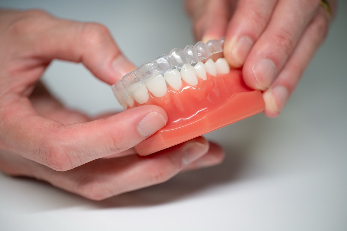 Holding a clear retainer against a model of the lower teeth