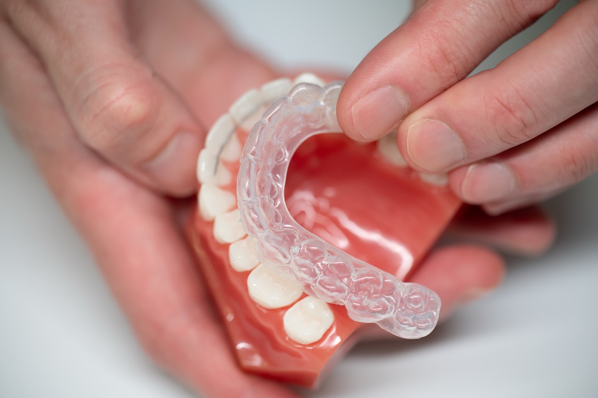 Close-up of a clear retainer held over a model of the lower teeth